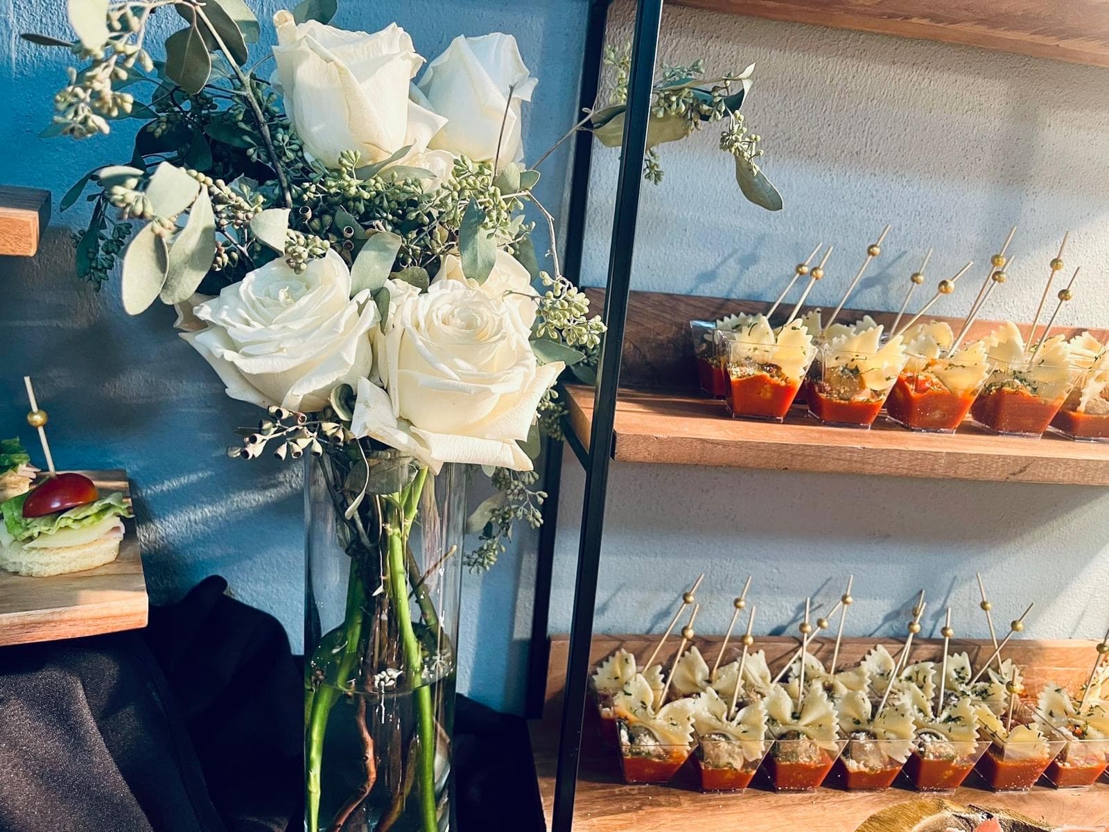 Event display with white roses and passed appetizers.